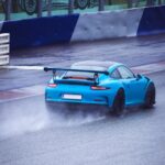 Luxury Cars - A sporty blue car speeds on a wet race track, ca #27513471